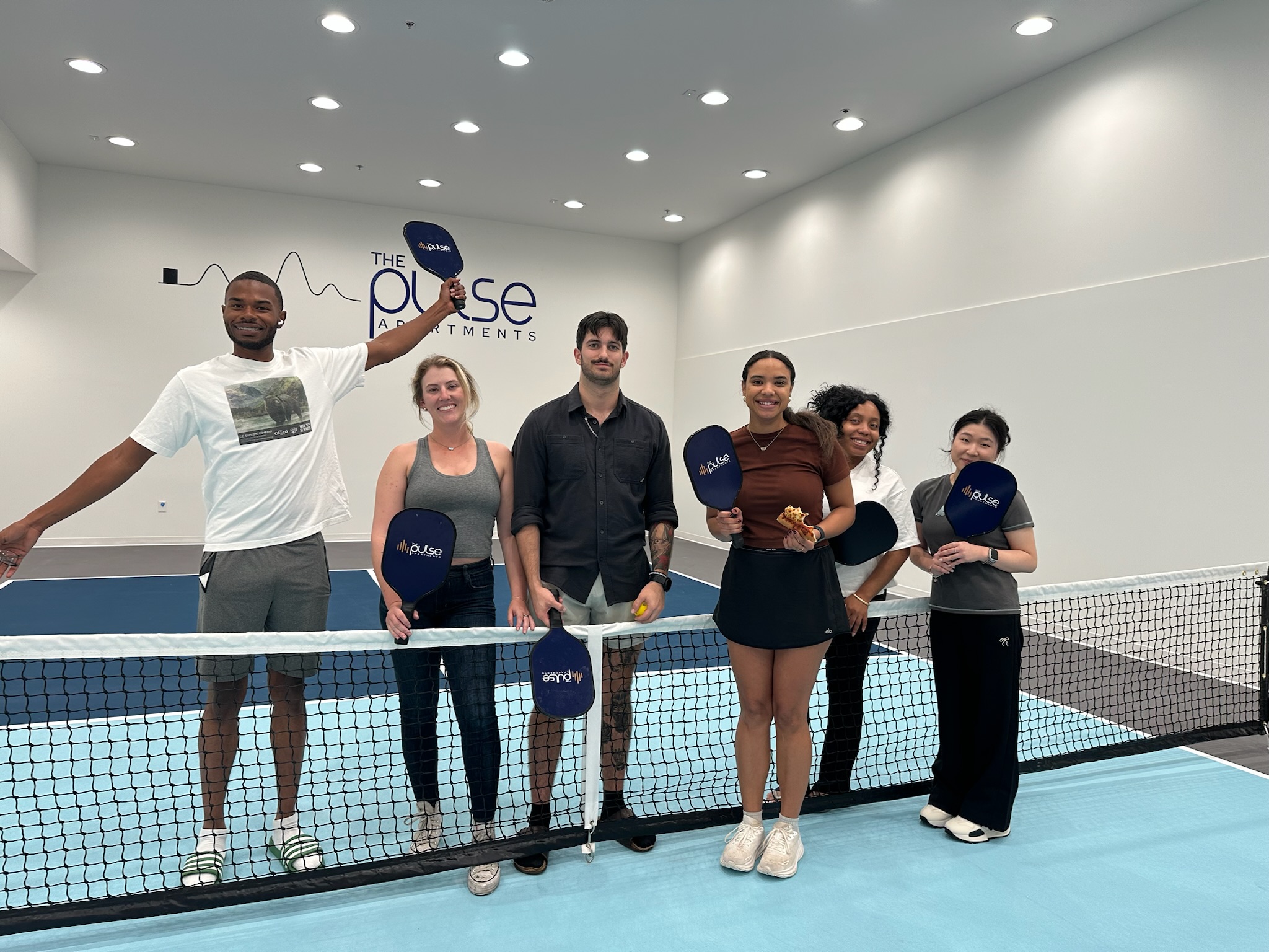 Residents holding branded pickleball paddles at The Pulse OKC.